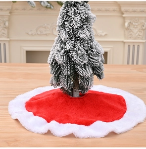 Close-up of red plush Christmas tree skirt with white border on wooden surface