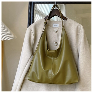 Detail of olive green PU leather tote bag hanging on a hanger with a beige jacket
