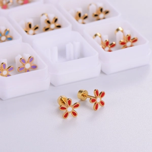 Macro shot of red and white enamel flower stud earrings with a gold-tone finish