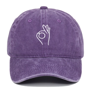 Detailed close-up of OK gesture embroidery on washed purple cotton baseball cap