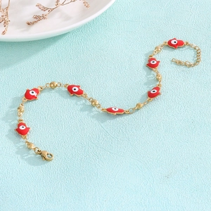 Macro view of gold chain bracelet with red Hamsa hand charms on a blue background