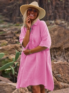 Detail of hot pink cotton linen shirt dress fabric and buttons in outdoor resort setting