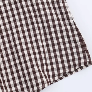 Close-up of brown and white gingham woven fabric with ruffled hem and fine stitching details