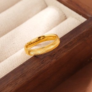 Nahaufnahme des goldfarbenen Titanstahlrings mit Textur auf einer beigen Samtunterlage