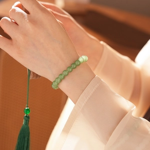 Detail of light green beaded jasper bracelet with a deep green tassel on a model wrist
