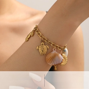 Close-up of a gold-plated bracelet with seahorse and sea turtle ocean-themed charms