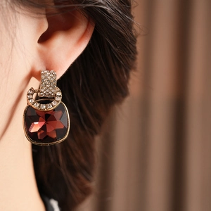 Close-up of vintage C-shaped earrings with red square crystal and crystal-set metal