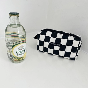 Detail of checkered canvas pencil case with top zipper and woven merciparis label