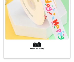 Close-up of white satin birthday ribbon with rainbow HAPPY text on a spool