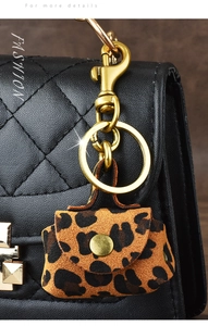 Macro detail of mini leopard print charm with gold clasp on quilted leather bag