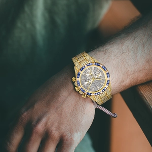 Macro shot of luxury gold watch dial with inset diamonds and rainbow gemstone bezel