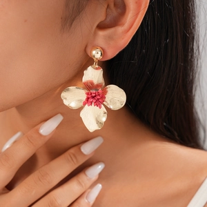 Close-up of vintage golden floral earrings with red centers worn by a model
