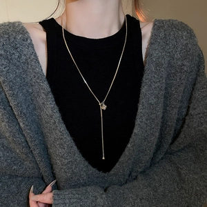 Close-up of a gold-plated Y-shaped necklace with a square zircon pendant on a model