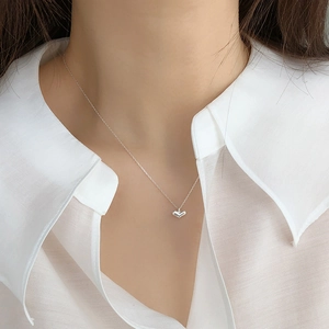 Close-up of a minimalist 925 silver heart pendant necklace on a woman neck