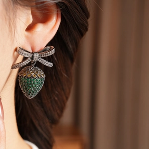 Macro side view of model wearing vintage bow and strawberry earrings with colorful crystals