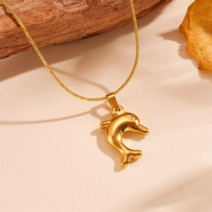 Gros plan d'un collier avec pendentif dauphin doré sur un fond en bois naturel