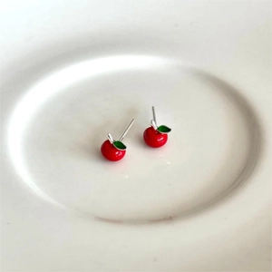 Minimalist 925 silver red apple stud earrings with green leaf details on a white dish