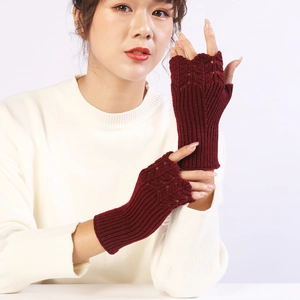 Close-up of wine red knitted fingerless gloves with scale texture and ribbed cuff