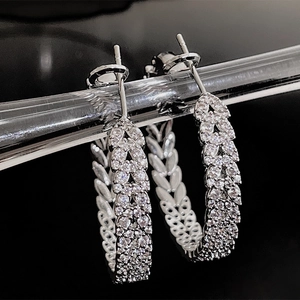Macro view of silver hoop earrings with cubic zirconia leaves and leaf texture detail