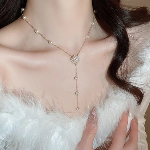 Détail d'un collier en perles en Y avec pendentif fleur en zircon et franges élégantes