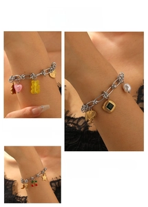 Detail of silver charm bracelet with yellow bear, pink heart and cherry pendants