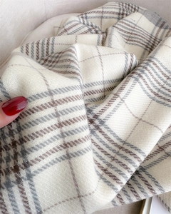 Close-up of thick plaid cashmere-like fabric showing soft texture and tassel details