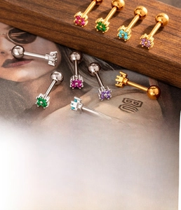 Detailed macro of flower cartilage piercings with colorful zircons in gold and silver