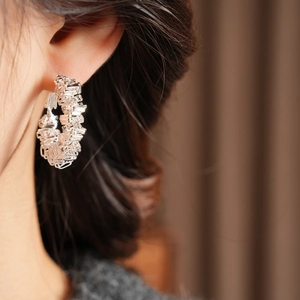 Close-up of silver geometric hoop earrings with textured layered metal wire design