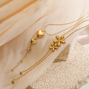 Elegant gold heart and flower pendant necklaces displayed on silk and stone