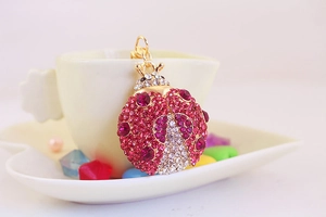 Makro-Detail eines goldenen Marienkäfer-Schlüsselanhängers mit rosa Strasssteinen auf Tasse