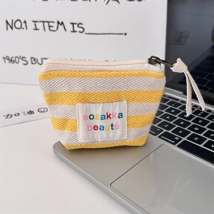 Detail view of yellow striped knit pouch for makeup and coins on a laptop keyboard