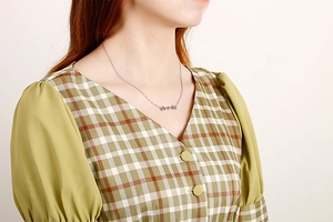 Detail of silver stainless steel necklace with double butterfly pendants on a model