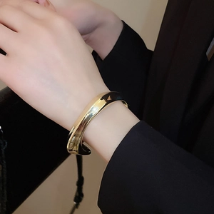 Gros plan d'un bracelet doré torsadé avec finition miroir polie porté sur un poignet