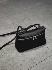 Minimalist black top-grain leather vanity bag with silver zipper and detachable strap