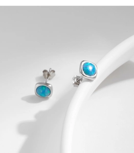 Macro shot of minimalist S925 silver stud earrings featuring square blue opal stones