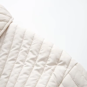 Close-up of premium white quilted cotton jacket showing detailed stitching and fine texture