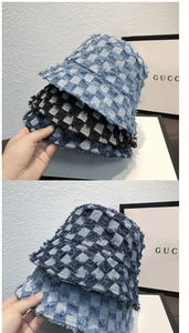 Detailed view of frayed denim checkerboard bucket hats in blue and black colors