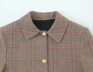 Close-up of houndstooth blazer notch lapel with embossed golden buttons and tweed texture
