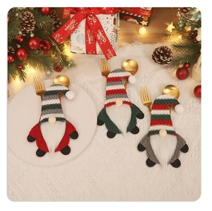 Three gnome Christmas cutlery holders with golden forks on a festive dinner table setting