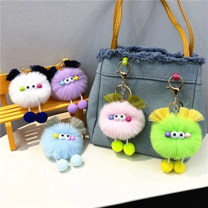 Detailed close-up of colorful plush monster charms on blue denim bag and yellow bench