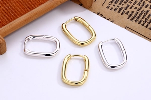 Detailed close-up of U-shaped gold and silver earrings on a rustic wooden tray