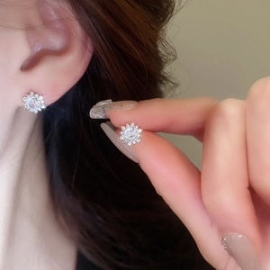 Close-up of sparkling cubic zirconia snowflake earrings worn for a minimalist elegant look