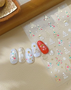 Detail of Christmas nail stickers with gold trees, snowflakes, and festive red accents