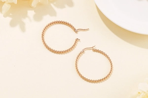 Detail view of rose gold beaded hoop earrings on an elegant warm background scene