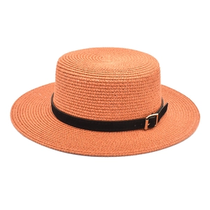 Detailaufnahme von orangem flachem Strohhut mit schwarzem Lederband und Goldschnalle