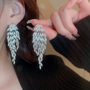 Macro shot of silver crystal feather earrings with dangling tassels on model