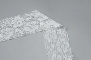 Dettaglio del pizzo floreale bianco su un abito aderente con scollo all'americana