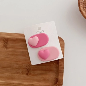 Close-up of pink heart hair clips set on a wooden tray with a minimalist design
