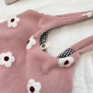 Detail of pink plush tote with floral embroidery, checkered lining and snap closure