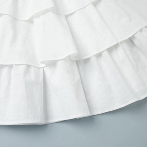Macro shot of tiered white linen skirt layers showing detailed fabric texture and stitching